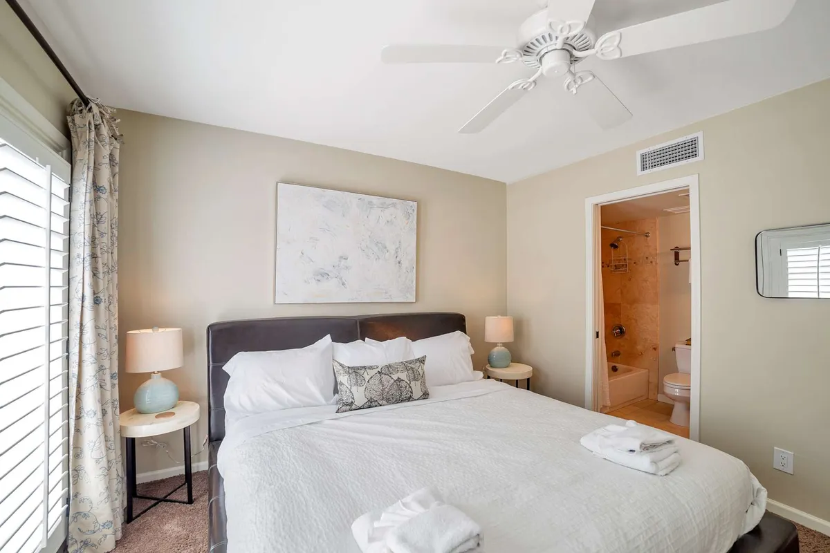 This image showcases a tranquil king-size bed with decorative pillows, soft lighting from bedside lamps, and calming wall art. The setting is serene and inviting, emphasizing comfort and a restful atmosphere, ideal for ending a productive day or enjoying a lazy morning.