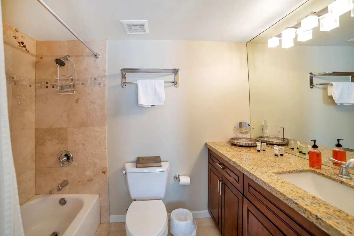 A serene bathroom setting with a granite countertop, mirrored vanity, a luxurious soaking tub, and a glass-enclosed shower. The space is clean, modern, and inviting—suggesting opportunities for self-care and pre-night-out routines.